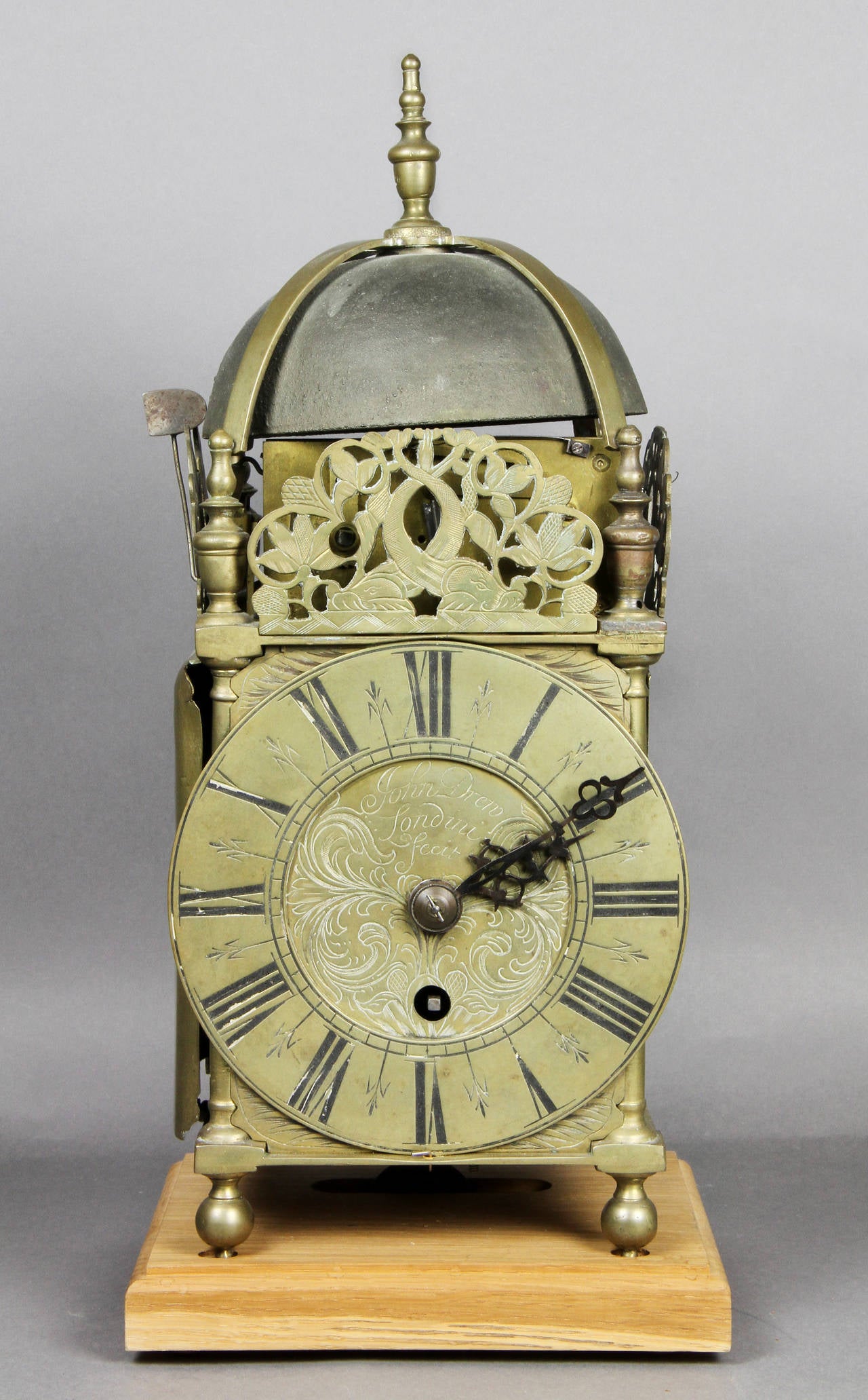 Domed top with bell and finial over dial with pierced decorated crest , bun feet