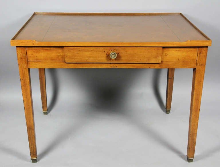 Rectangular top with tooled brown leather over a single drawer, raised on straight square tapered legs, brass sabot.