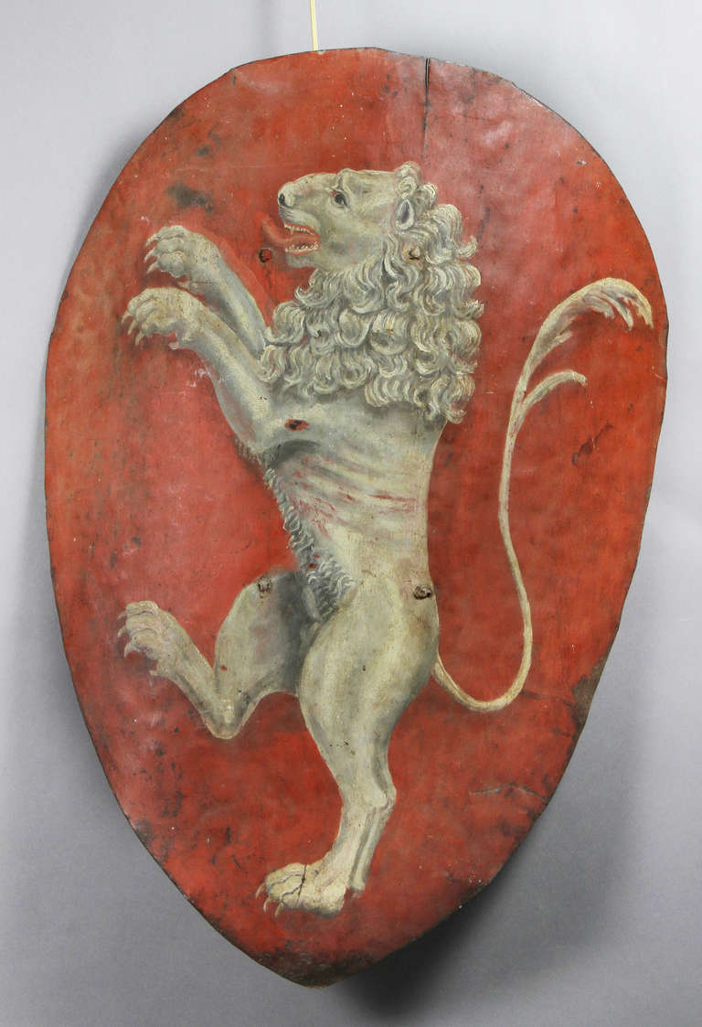 Shield form painted red with a rampant lion in a grisaille pallette.
