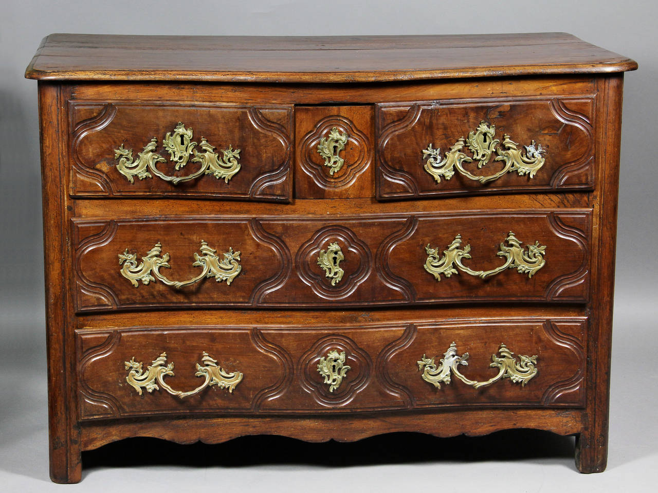 Serpentine top over a pair of drawers with central hidden drawer over two conforming drawers ,all with panelled fronts ,  panelled sides , shaped feet.