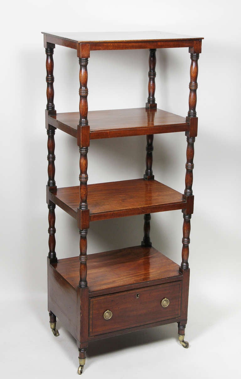 Rectangular top over two shelves , the base with shelf and drawer , turned legs , casters.