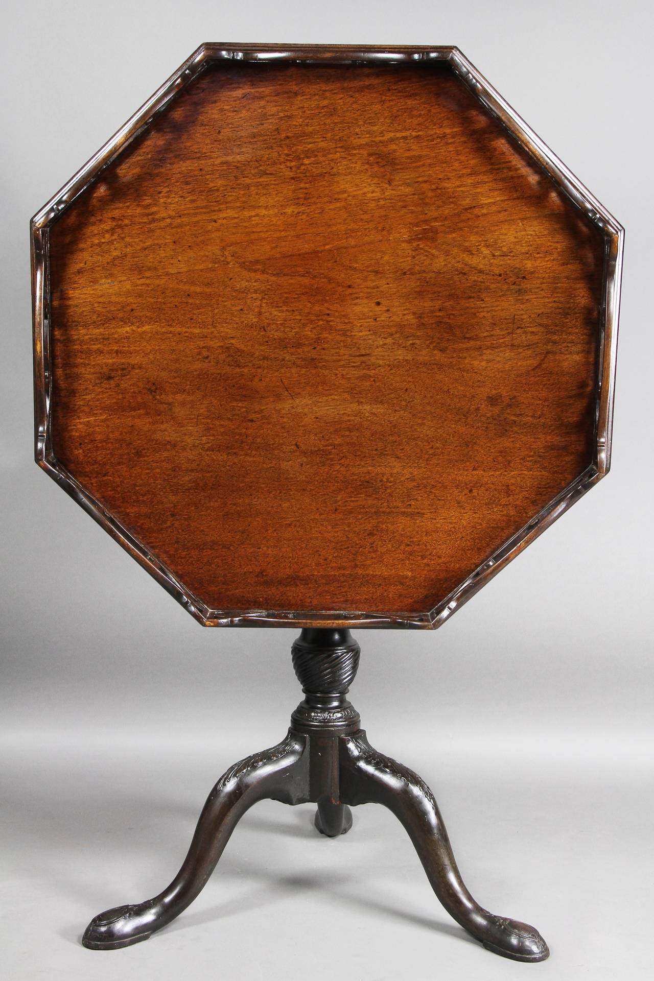 Octagonal top with carved and pierced gallery raised on a turned and carved support ending on a tripod carved base, pad feet