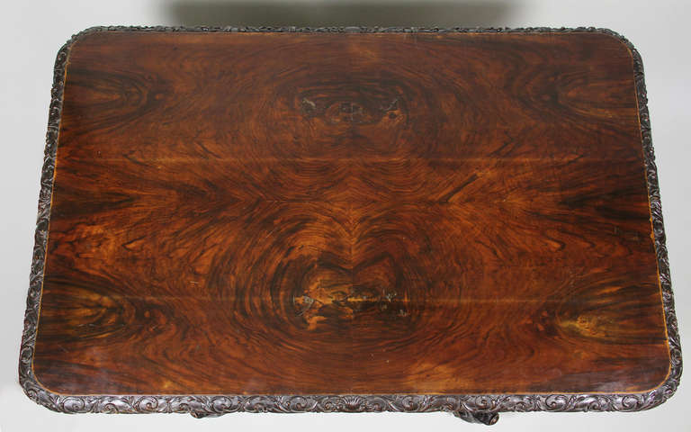 Rectangular top with carved edge over a carved support, the legs carved as dolphins terminating on scroll feet.