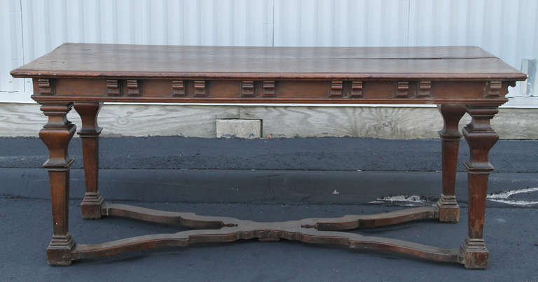 Zwei Bretter über einem Fries mit aufgesetzten Kragsteinen, quadratische, verjüngte und blockgedrehte Beine, verbunden durch eine X-förmige Bahre.