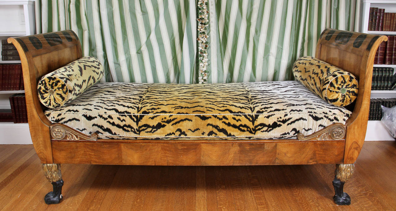 Typical form upholstered in old world weavers tiger velvet, crest of each end with penwork panels, raised on ebonized and giltwood paw feet.