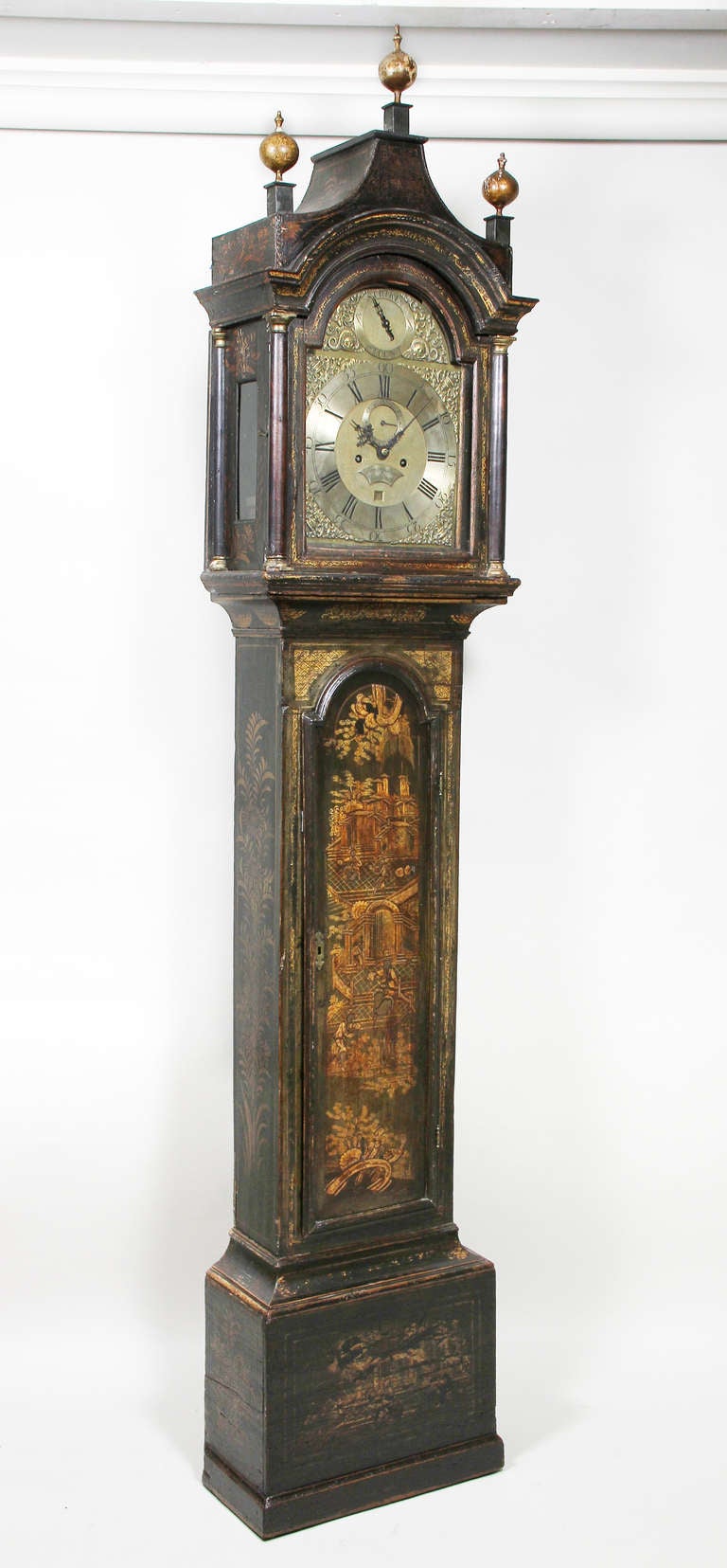 Arched bonnet with three wood finials over a glazed arched door enclosing a brass dial signed Benjamin Sudlon, Yarmouth, the centre case with arched door, plinth base.
