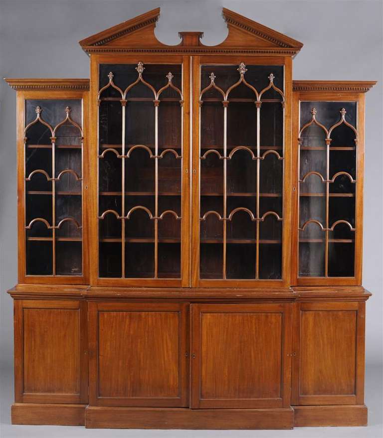 Broken arched triangular stepped cornice above a pair of doors with arched mullions flanked by another shorter conforming pair, the base with a pair of panelled doors flanked by a narrower pair, plinth base. Provenance: Hyde Park Antiques, Ltd., New