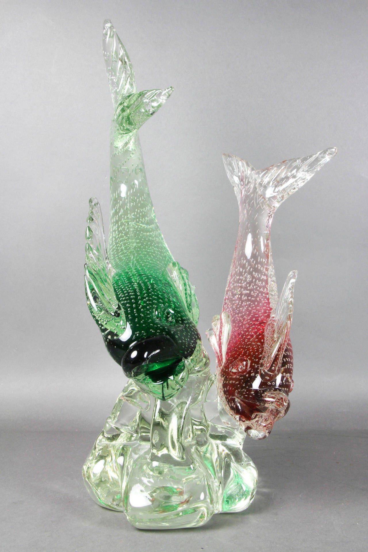 One red and one green fish on a molded glass base.