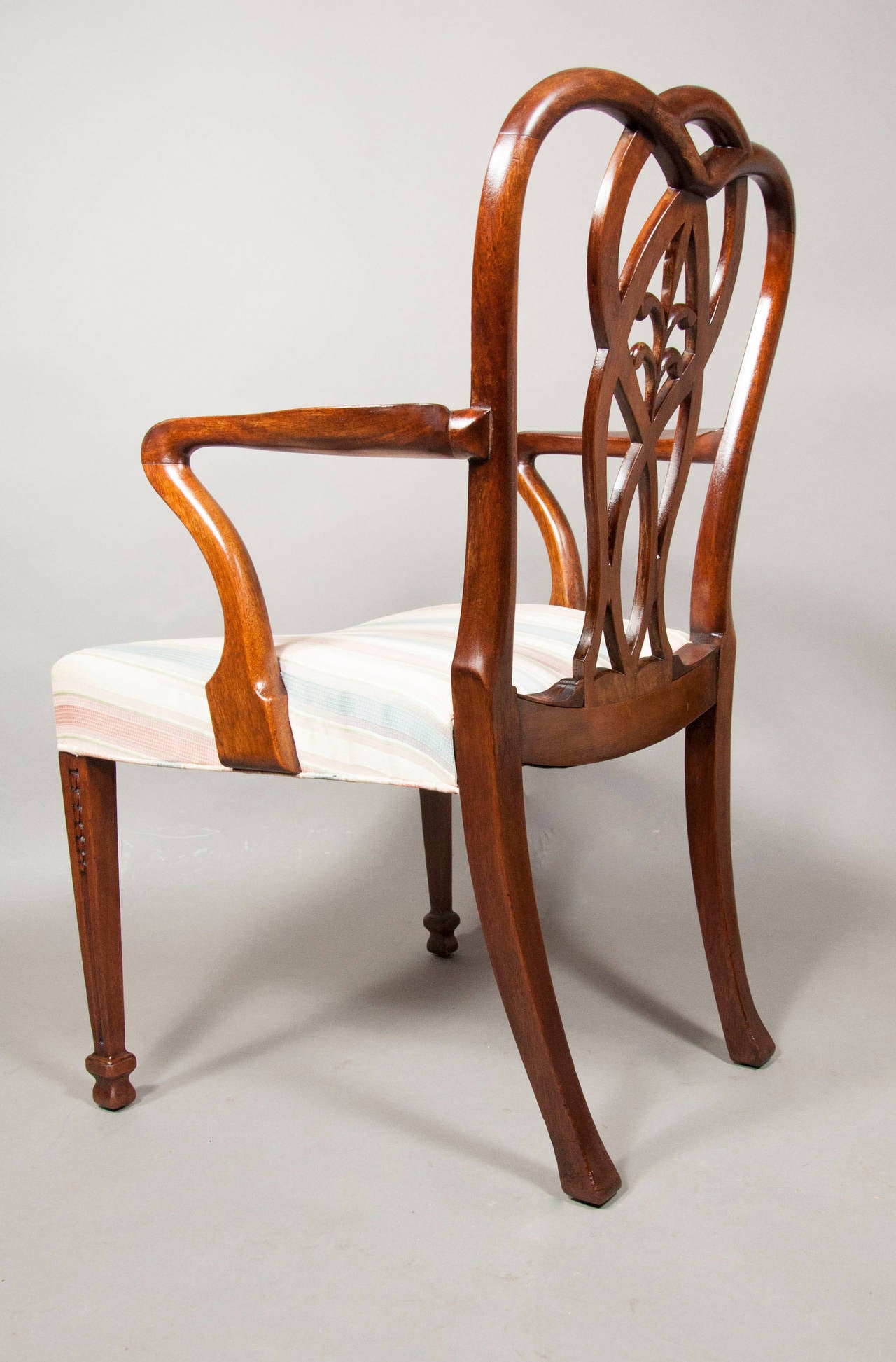 Each with an interlaced back with carved bellflower and Prince of Wales plume , 
upholstered seat raised on square tapered carved legs. Pair armchairs and ten side chairs. By Howard and Sons , Berners St , London