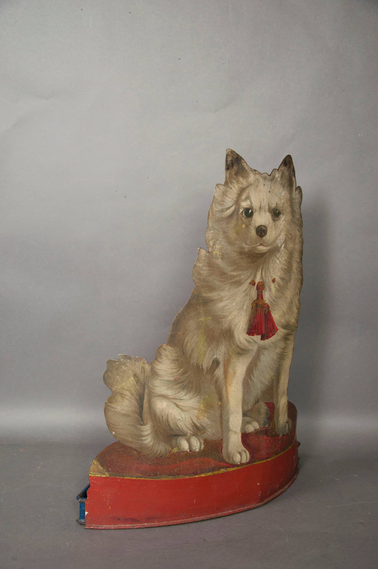 Seated dog with red tassel around his neck.