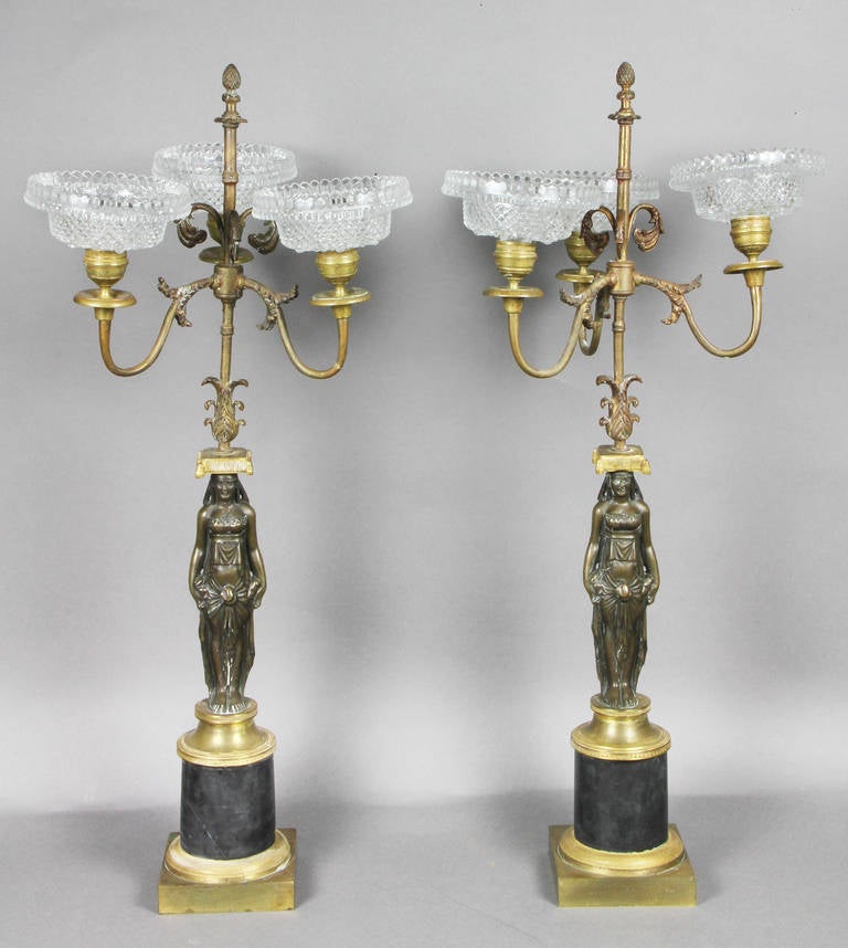 Each with three arms with cut glass bobeche above standing maidens and circular plinth base