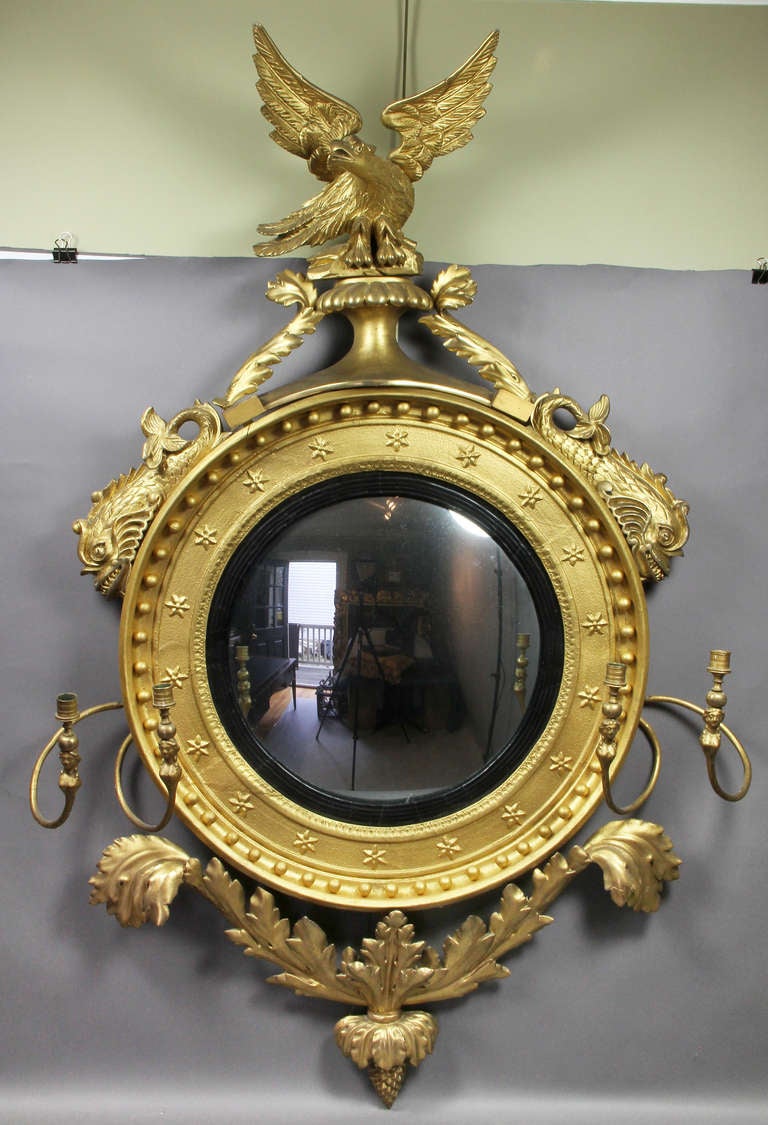 Circular plate set in a star and ball frame with eagle finial over a pair of dolphins , flanking two pairs of candle arms , ending in acanthus leaves and pinecone.