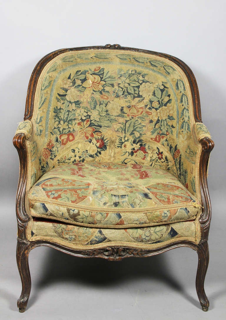 The arched back with central flower carving and down scrolled carved arms , raised on cabriole legs. Original tapestry upholstery.