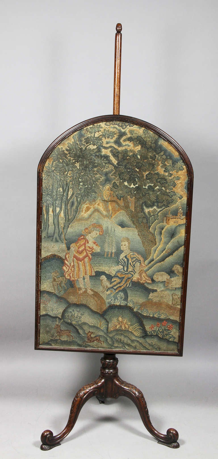 18th century needlepoint panel with two figures in a landscape, raised on a finely carved support with tripartite legs with scroll feet.