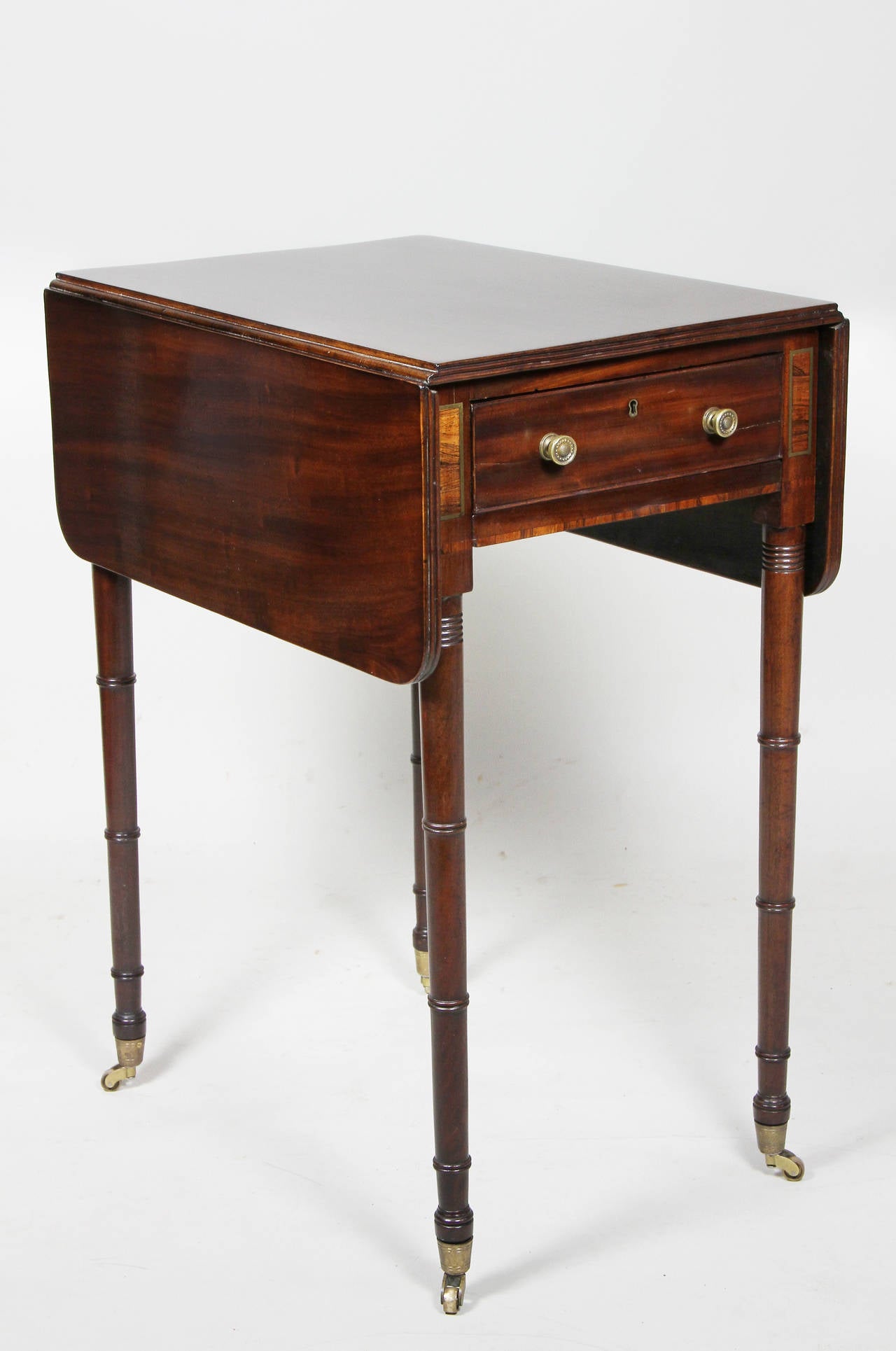 With rectangular drop leaves over a single drawer and opposing false drawer flanked by rosewood and brass inlaid panels , raised on bamboo turned tapered legs with casters.