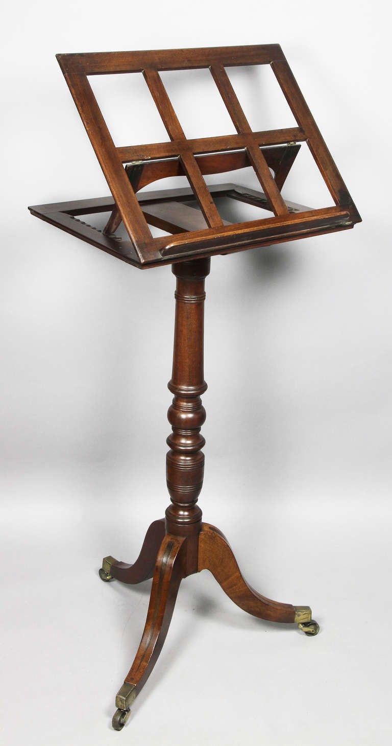 Ratcheted book holder over a turned support , tripartite legs , brass casters.