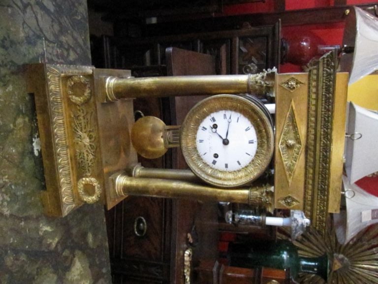 Corinthian columns flank this gilded clock with enamel dial.  Signature on dial states 