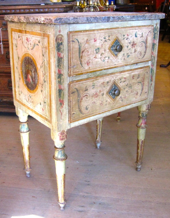 Polychrome painted Italian chest with scrollwork on drawers.  Each side panel is adorned with a circular painting of flowers draping from a basket.