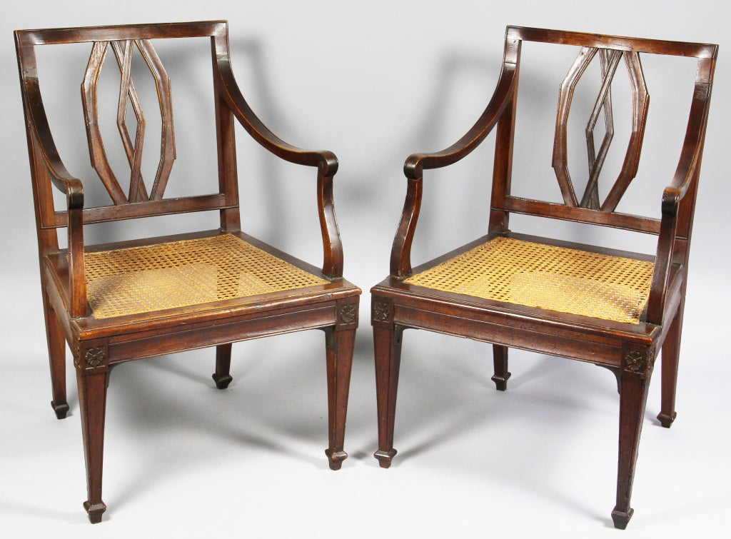 Each with a rectangular back with open trapezoidal splat, caned seats, raised on square tapered legs headed with carved paterae.