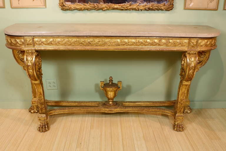 A large and impressive French giltwood console table in the Louis XVI neoclassical style (circa 1880), featuring a finely-carved vitruvian scroll apron, acanthus and laurel leaf decoration, carved Grecian urn finial on stretcher and paw feet. Table