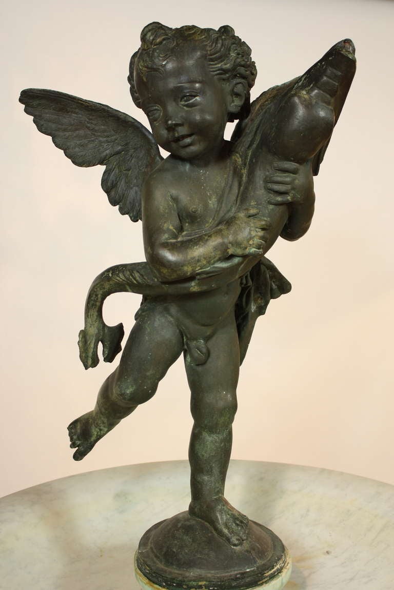 This elegant Italian carved marble fountain features a patinated bronze figure of a putto holding a dolphin, a copy of a 