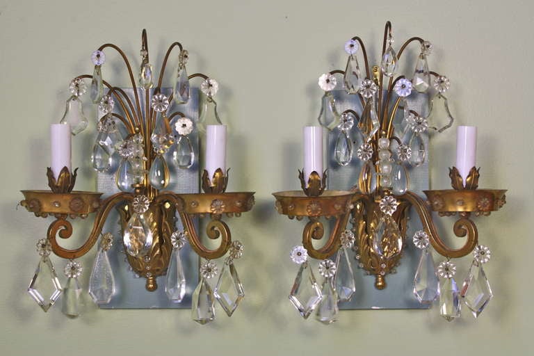 Pair of French gilt-bronze and crystal sconces by Maison Baguès.  There is a wonderful selection of interesting and high-quality crystals, particularly in the central spray. Crystal beads decorate the bottom leaf section.  The sconces also include