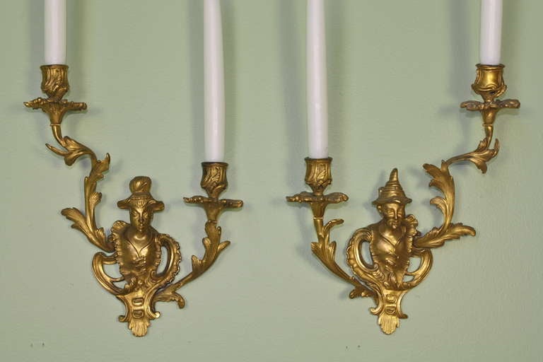 Pair of French Louis XV style gilt bronze sconces with figures of an oriental couple, the woman with her hair in a bun and the man with a hat (circa 1870). Foliate details enhance the arms.