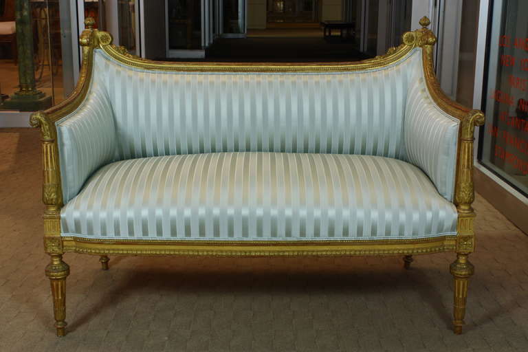 An elegant, petit French giltwood canapé or settee in the Louis XVI style (circa 1880). The canapé has been recently reupholstered in new striped silk Louis XVI re-edition fabric by Scalamandre. The canapé has a nicely sloped back, terminating in