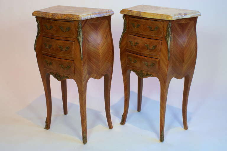 A nice pair of French Louis XV style night tables or chevets, with marble tops and three drawers.  Parquetry veneered in tulipwood (in French, 