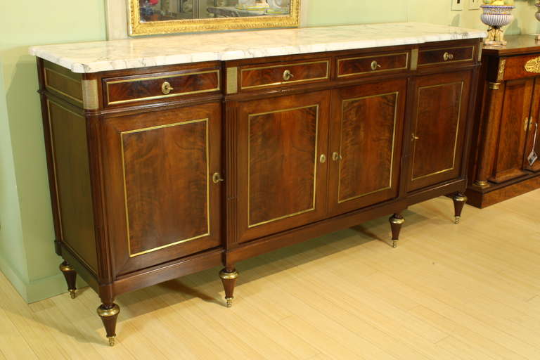 An elegant French Louis XVI style buffet or enfilade with book-matched flame mahogany doors, four drawers, and three cabinets (each with a single inner shelf).  The top is a nice piece of 1.25