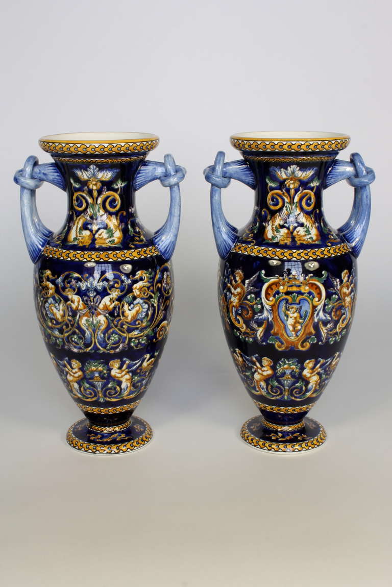 Pair of highly-decorative hand-painted faience two-handled vases in the Italian style by the French manufacturer Gien.  The vases feature a cobalt blue (