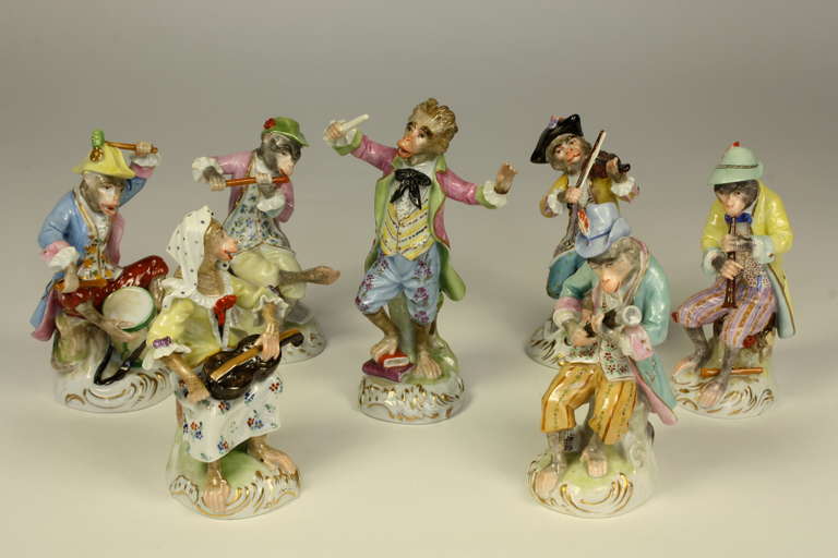 A lovely, highly-detailed seven piece Desden porcelain monkey band orchestra attired in 18th century style costumes, seated on rocaille bases.  The original 18th century monkey orchestra by Meissen was reputed to have been caricatures of Viennese