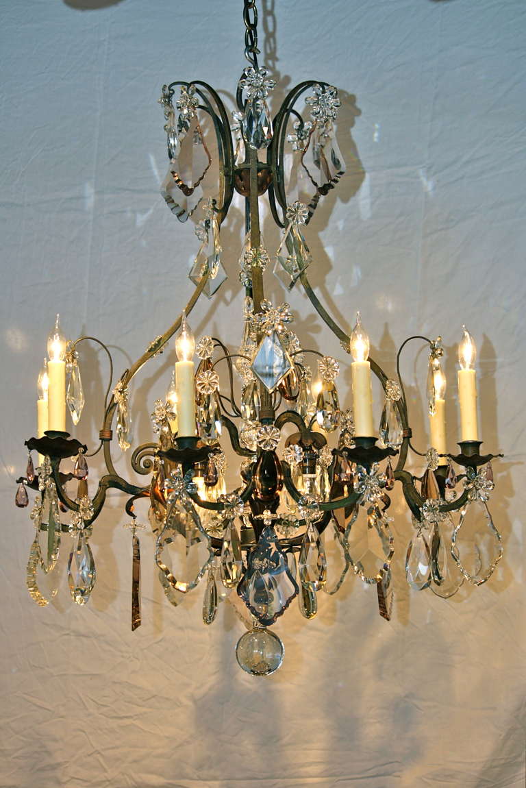 An impressive French wrought iron and tole leaf chandelier, in cage form with central spear by Maison Baguès (early 20th century). This chandelier has been newly-electrified with eight lights (plus four inner lights), and features an array of clear,