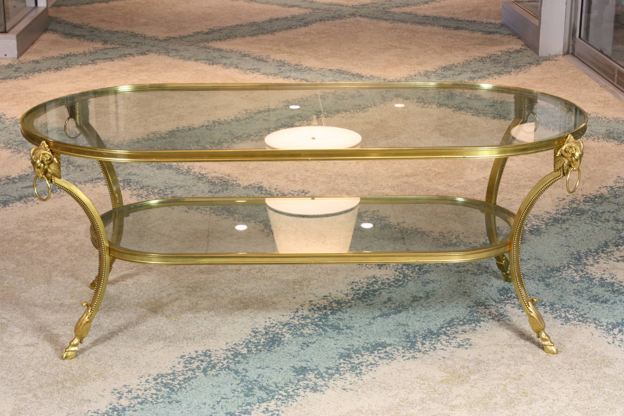 French gilt bronze coffee table with nicely-cast rams' head detailing and hoof feet, acanthus leaves, and pearl beading along the legs (Maison Jansen, circa 1960's).  Two tiers have thick glass tops.  This table is quite heavy.