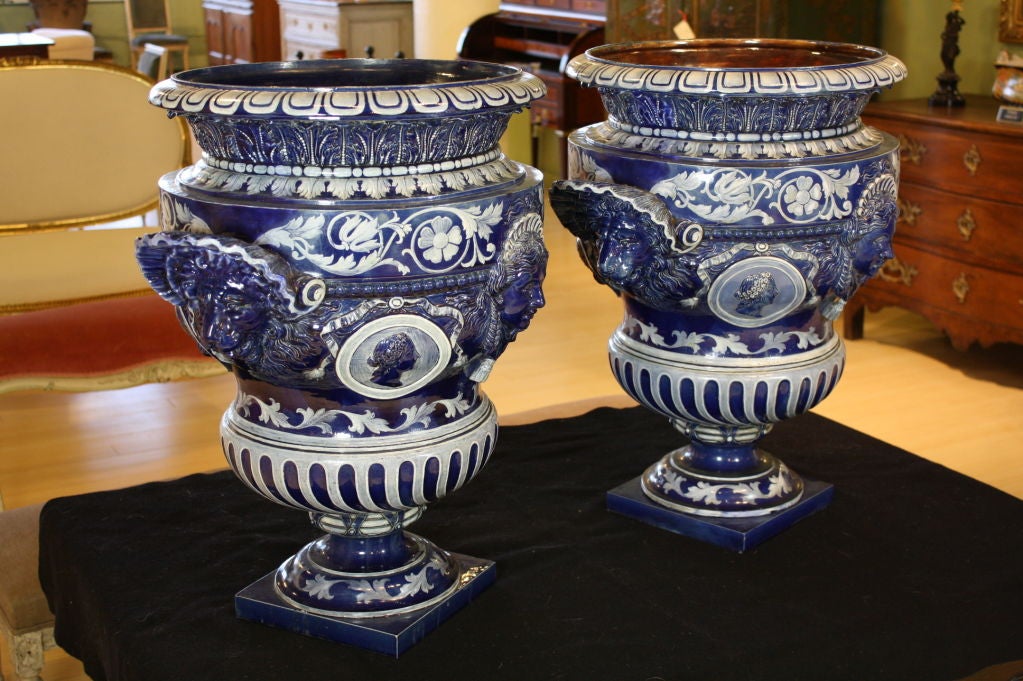 Pair of spectacular campagna form urns with vibrant cobalt blue glaze from Verona Italy. The urns feature hand-painted neoclassical detailing, including acanthus leaves and rinceaux designs, and heads of minerva, lion masks and Roman intaglio