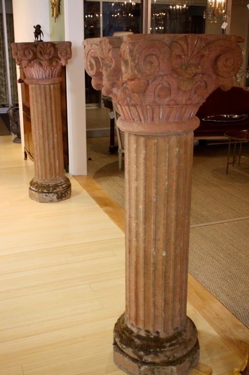 Paire d'impressionnantes colonnes sculptées en pierre rose provenant d'un cloître du sud de la France. Les colonnes sont chacune en deux parties avec un chapiteau séparé. Les chapiteaux sont de forme romane avec des motifs de coquilles, de feuilles