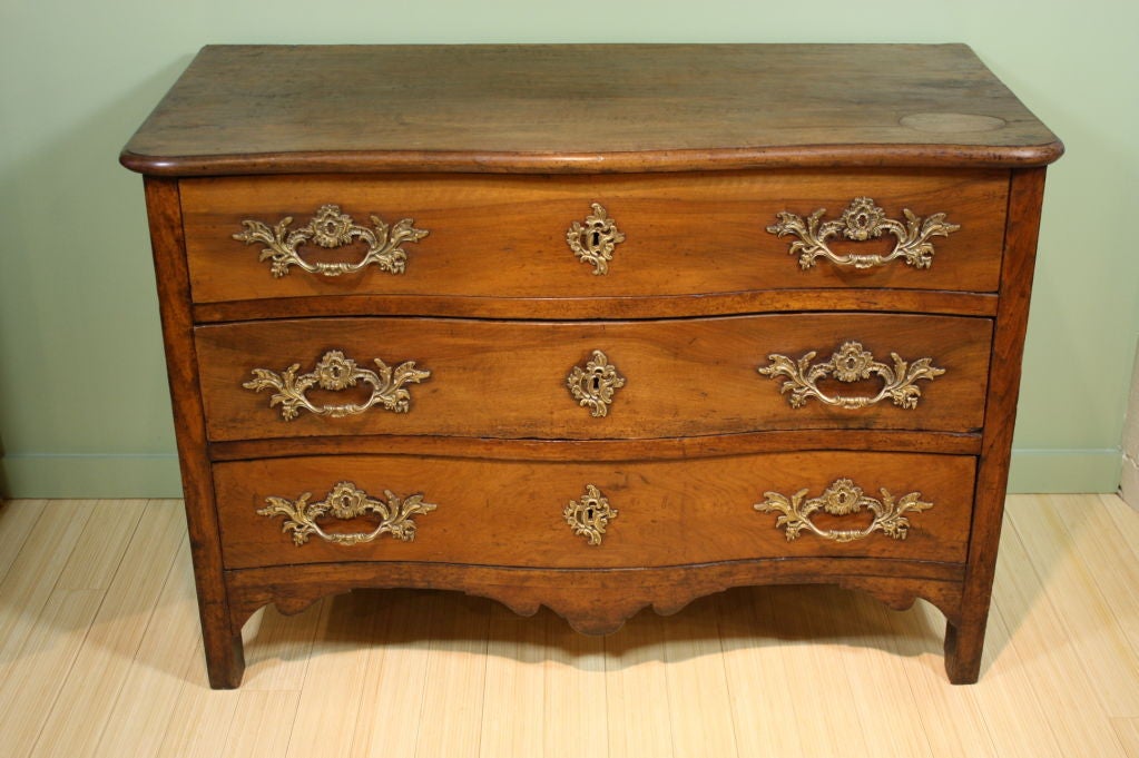 French Louis XV period walnut commode in galbee form, three drawers and gilt bronze foliate style mounts. The commode has a very nice, mellow patina. The top is one large, solid piece of walnut unlike anything you could find today, with an