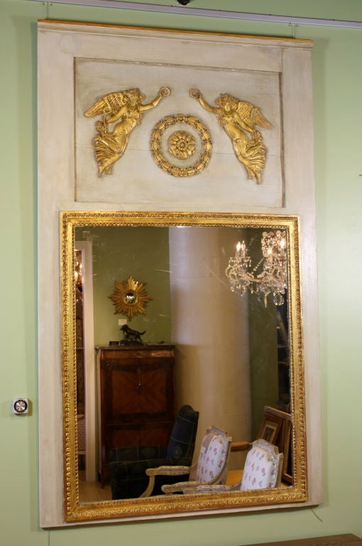 French Directoire period polychrome and parcel gilt trumeau mirror. The trumeau features winged figures of Victory, the left image holding a trumpet and the right image holding a palm leaf. A central rosette is set in a wreath of bees. The glass in