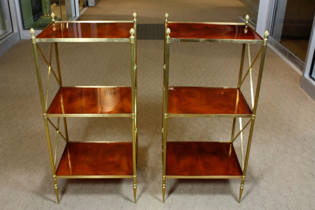 Pair of French brass etageres with neoclassical details, including acorn finials, and original orange marblelized bakelite shelves (attributed to Maison Jansen).