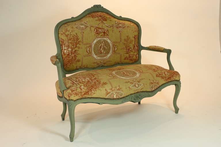 French Louis XV style polychrome canapé or settee (Circa 1880), recently upholstered in a gold and red Braquenie classical Toile de Jouy fabric and nail head trim.  Carved flowers on the crest rail, seat rail and knees ornament the piece. 