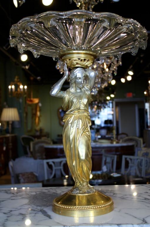 French neoclassical gilded and silvered bronze caryatid supporting a crystal coupe by Baccarat. The bronze work is very finely chased, gilded and silvered. Note the caryatid's hair and the folds in her robe. The bronze support for the coupe held by