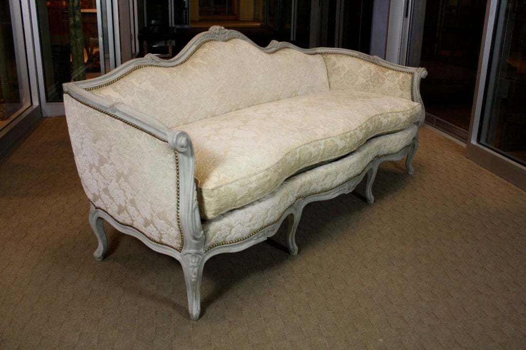 French Louis XV style painted sofa by Maison Jansen, with separate cushion, cut velvet fabric and brass nail head trim.  Beautifully carved details include scrolled arms with acanthus leaves, floral and foliate carving on crest rail and seat rail.