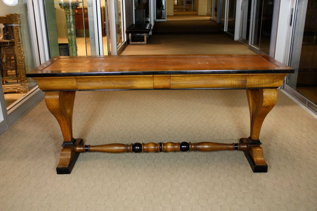 Austrian Biedermeier table in light walnut with nice ebonized details, a turned stretcher, elegant profile at the sides, with nice tooled leather top, and containing two hidden drawers.