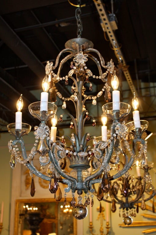 A pair of painted wrought iron and crystal chandeliers, design attributed to Maison Bagues, with palm leaves decorating the central column and arms. Bead chains are strung along the arms and upper branches, with crystal flowers and drops, some
