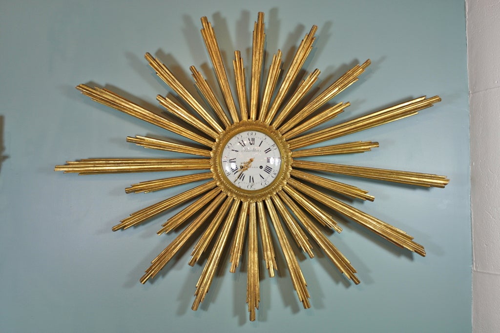 This magnificent giltwood sunburst wall clock is very unusual for its impressive size of over five feet wide.  The clock movement is in working condition and strikes on the hour and half-hour.  The movement has a silk suspension and count wheel, and