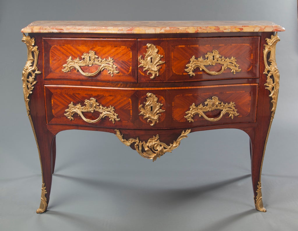 A lovely French Louis XV period commode with parquetry detailing, exuberant rococo gilded bronze mounts and breche d'alep marble top (Circa 1750), stamped by the listed 18th century ebeniste, Jean Baptiste Saunier.  The commode has three drawers