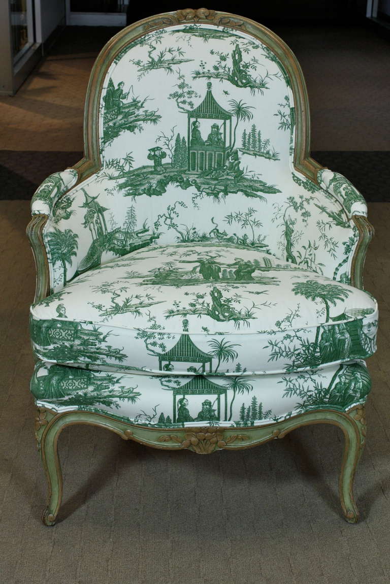 A generous French Louis XV period armchair or bergere (Circa 1760), newly-upholstered in Scalamandre green and white Chinoiserie pattered toile fabric, with separate down-stuffed seat cushion.  The bergere's frame is painted green and light brown,