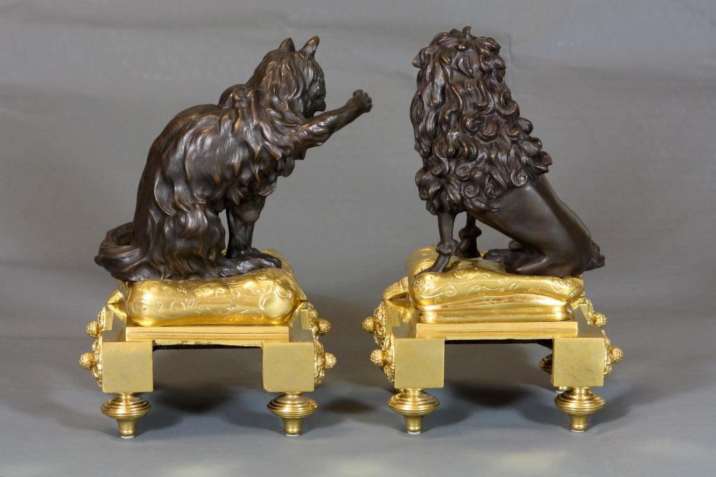 A lovely pair of gilt-bronze and patinated bronze chenets featuring a poodle and persian cat, each sitting on tasseled pillows and neoclassical plinths with rosettes and toupie feet.  The bases retain their original mercury gilding.  The chenets are