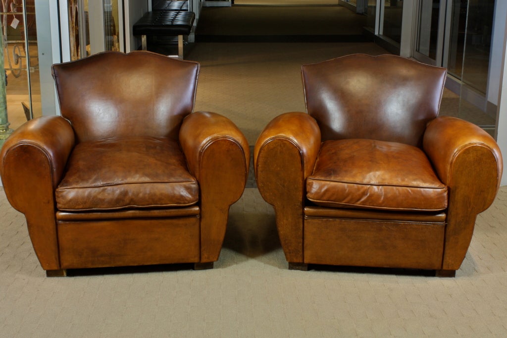 A nice pair of French leather club chairs with mustache backs, well-proportioned with separate down-stuffed seat cushions (mid-20th century).