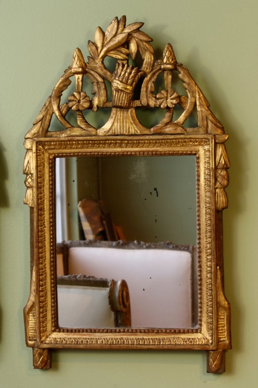 Petit miroir trumeau en bois doré d'époque Directoire avec cartouche en forme de gerbe de blé et autres détails néoclassiques (Circa 1790).  Joli verre au mercure ancien.  Un miroir 